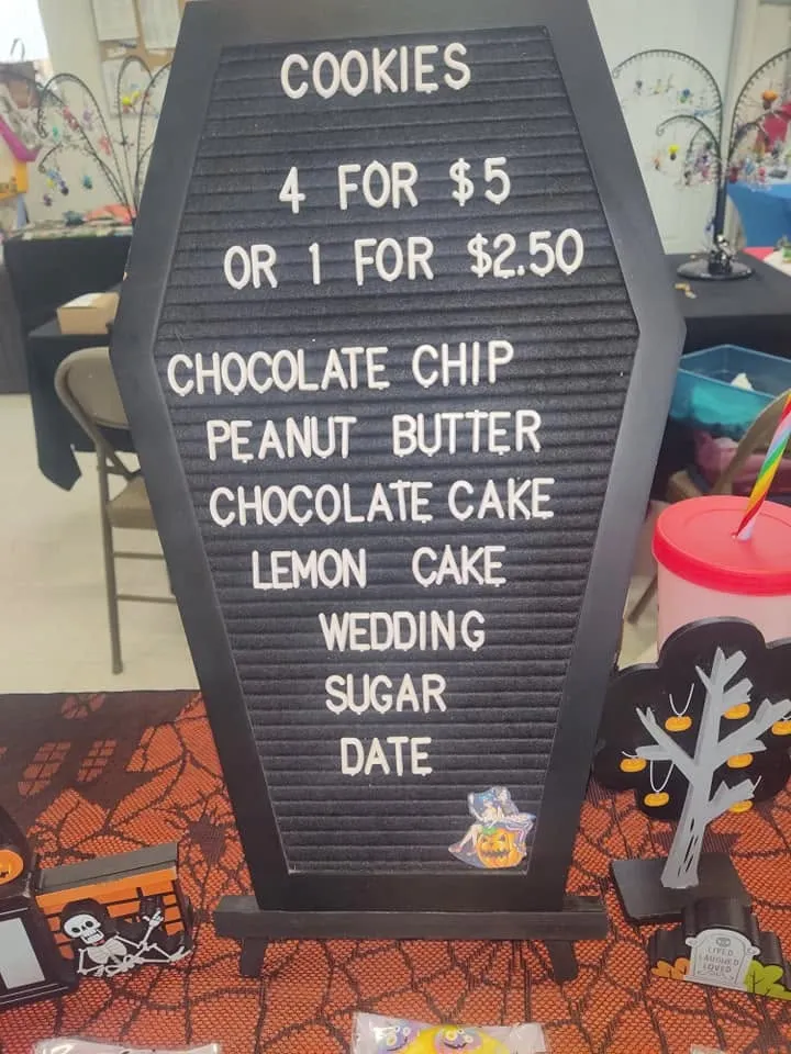 Coffin-shaped letterboard menu listing cookie flavors at a vendor booth